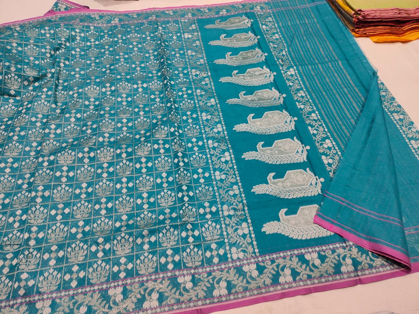 Teal fabric with white patterns on a light pink background
