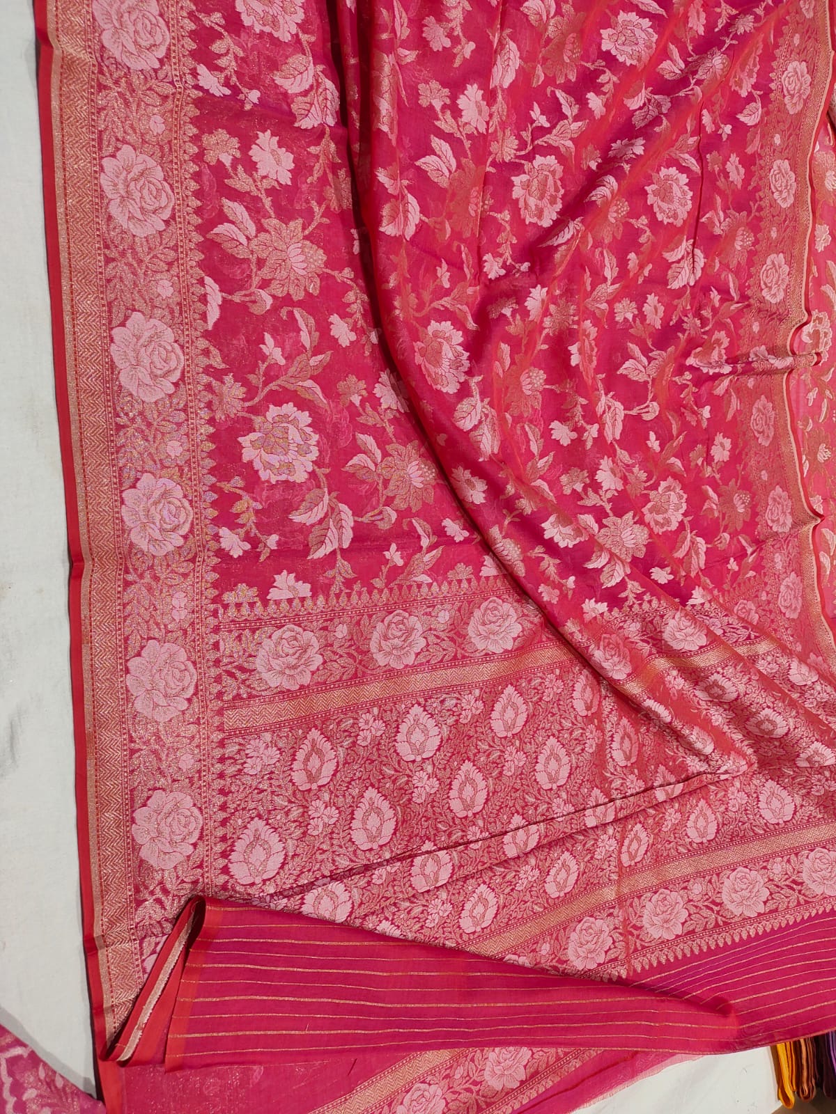 Pink saree with white floral patterns on a white background