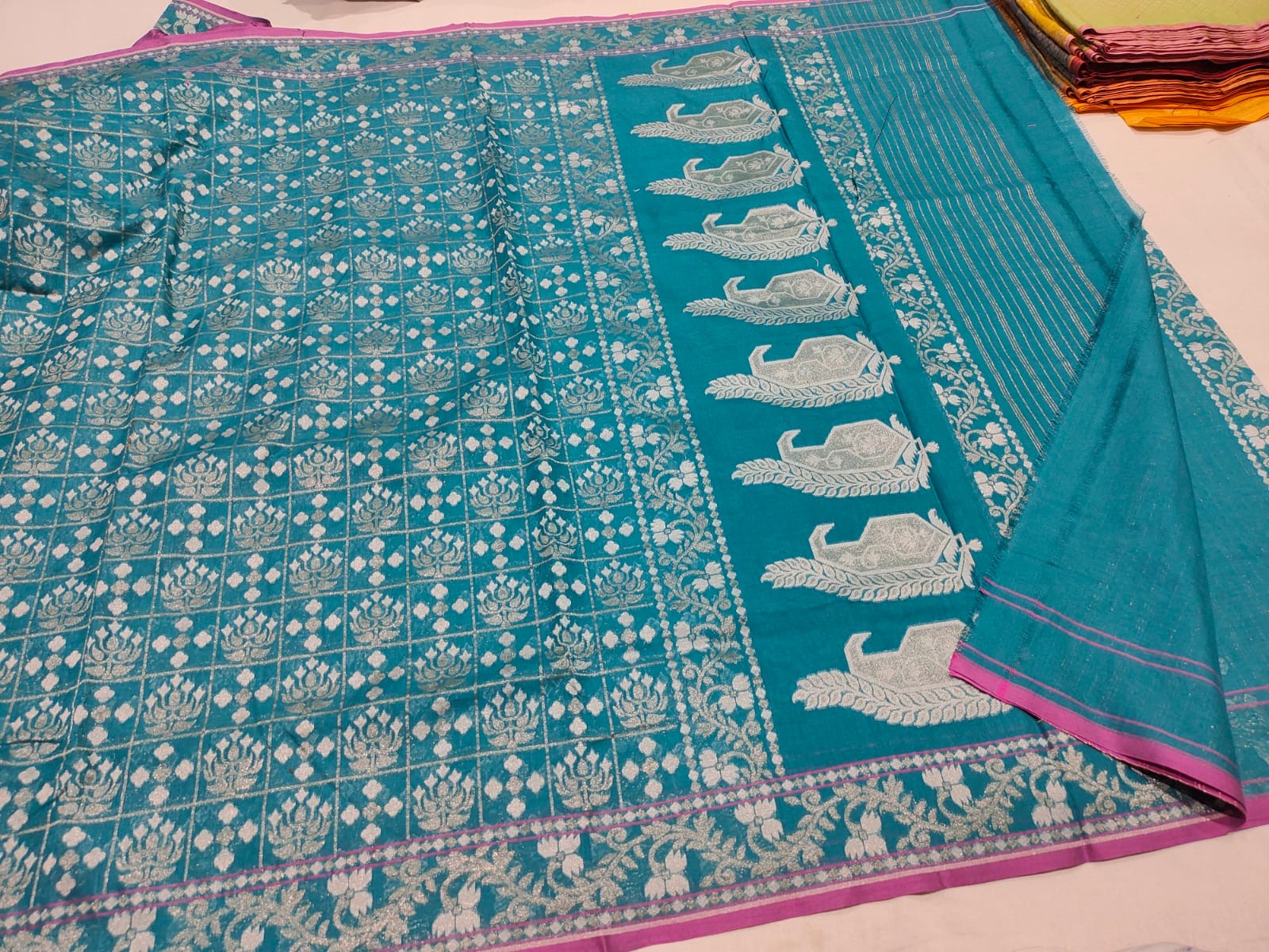 Teal fabric with white patterns on a light pink background